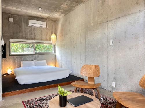 a bedroom with a bed and a table and a chair at Stäy Hotel Nakijin in Nakijin