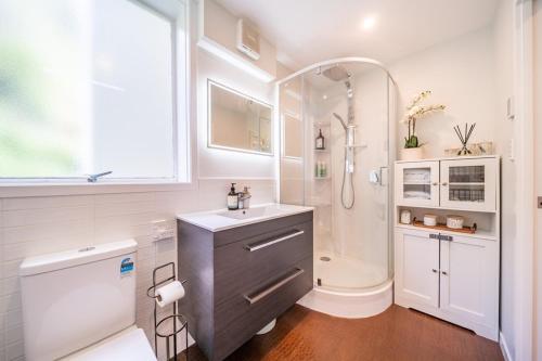 a white bathroom with a sink and a shower at Luxury Beachfront Apartment - Private Upper Suite in Wellington