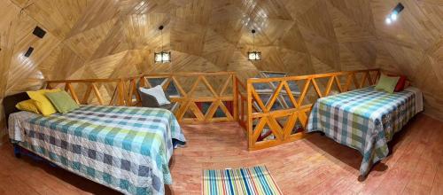 a room with two beds in a wooden cabin at Domo loft puacura - tinaja disponible in Castro