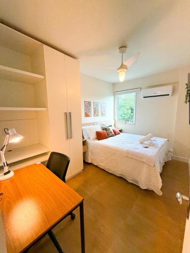 a bedroom with a bed and a desk and a table at Encanto da Praia LUXO Ap 2 qts Pe na Areia Camboinhas in Niterói