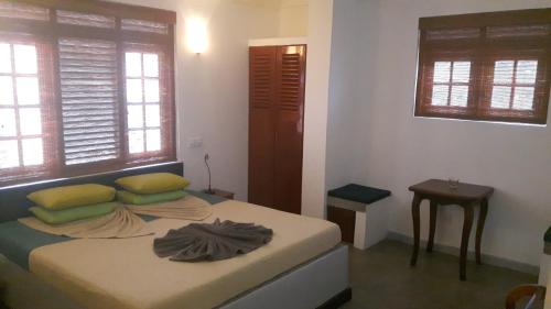 a bedroom with a bed and a table and windows at Seagreen Guesthouse - Galle Fort in Galle