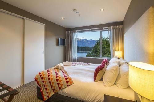 a bedroom with a large bed with a window at LakeRidge Queenstown by Staysouth in Queenstown