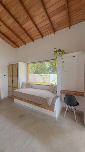 a bedroom with a bed with a window and a chair at Villa Palm in Rekawa