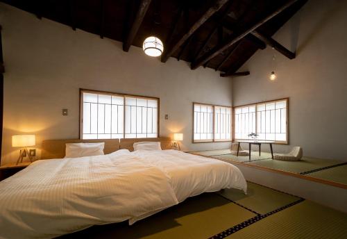a bedroom with a large white bed with two windows at Ebisuya / Vacation STAY 5851 in Kofu