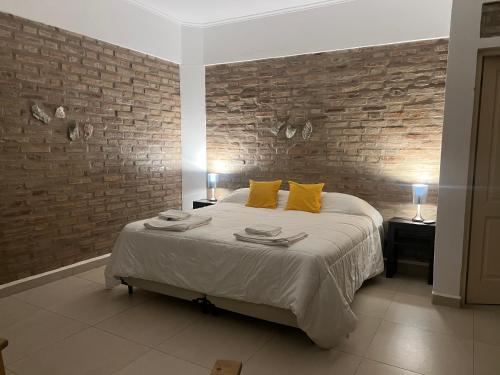 a bedroom with a bed and a brick wall at Anicca Posada in San Marcos Sierras