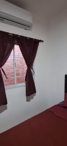 a bedroom with a bed and a window with curtains at La Guarida 3 in Concepción