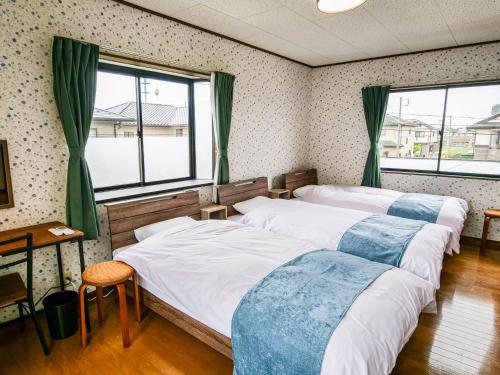 three beds in a room with two windows at Villa228KASAMA in Kasama