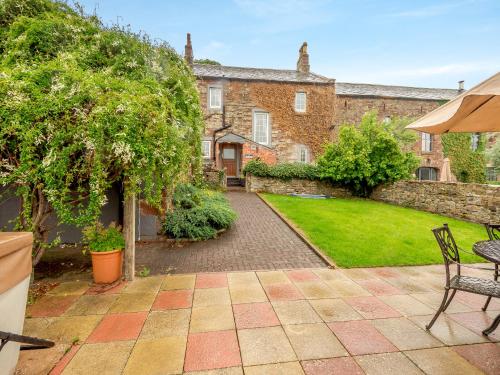 a garden with a patio and a house at Halls Bank Farm in Plumbland
