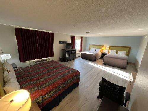 a hotel room with two beds and a television at Wesley Inn and Suites in Wichita