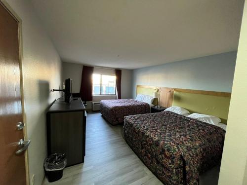 a hotel room with two beds and a television at Wesley Inn and Suites in Wichita