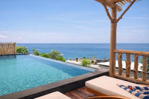 a swimming pool with a view of the ocean at Abing Villas Spa & Beach Bar in Amed