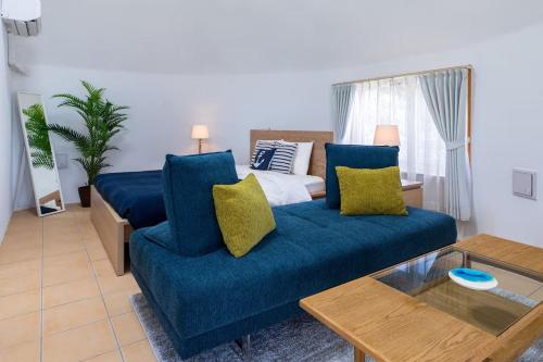 ein Wohnzimmer mit einer blauen Couch und einem Bett in der Unterkunft Uruma Dome Okinawa in Uruma
