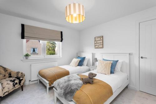 a bedroom with two beds with a teddy bear on the bed at Paradykes House in Loanhead