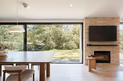 a dining room with a table and a fireplace at Treetop House in Crafers