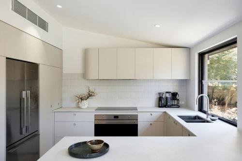a white kitchen with white cabinets and a window at Treetop House in Crafers