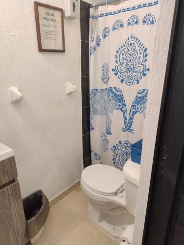 a bathroom with a toilet and a shower curtain at Bungalow Turrent, a 5 minutos de Playa Mocambo in Veracruz