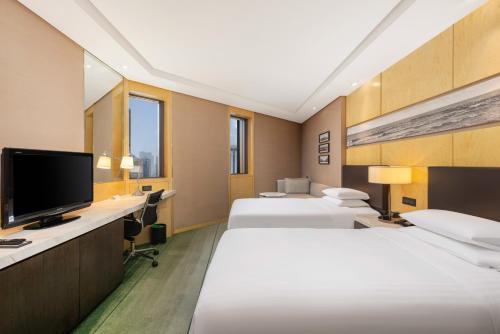 a hotel room with three beds and a flat screen tv at Shanghai Qilu Hotel in Shanghai