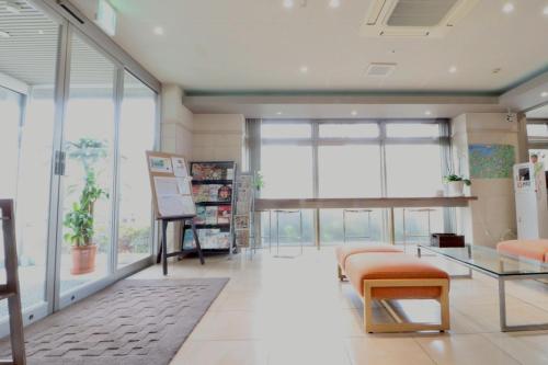 a waiting room with a bunch of chairs and windows at ホテルクオーレ敦賀 男性専用の大浴場サウナをご用意 in Tsuruga