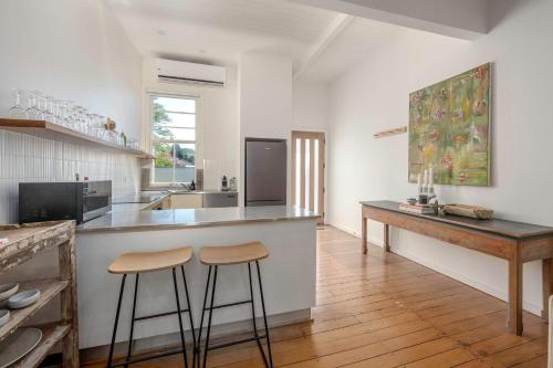 a kitchen with a counter and two stools in it at Luxury Couples Stay Bangalow l Nova Escapes in Bangalow