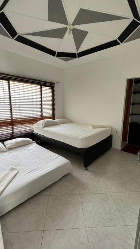 two beds in a room with a ceiling at Finca Turística VILLA NELLA in Acacías