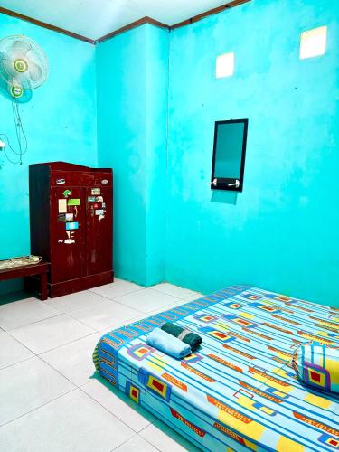 a blue bedroom with a bed and a tv on the wall at Kopinka in Yogyakarta