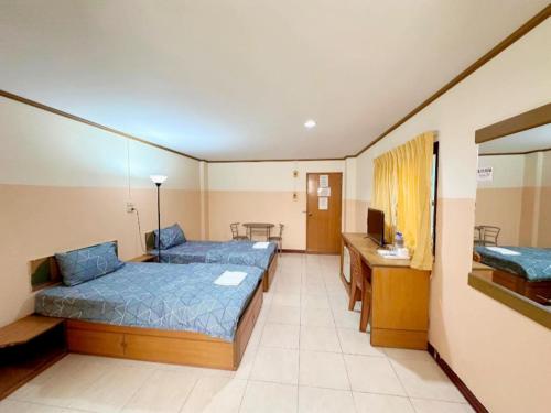 a hotel room with two beds and a television at เพิ่มพูนแมนชั่น พิษณุโลก Phoempun Mansion in Sathani Phitsanulok