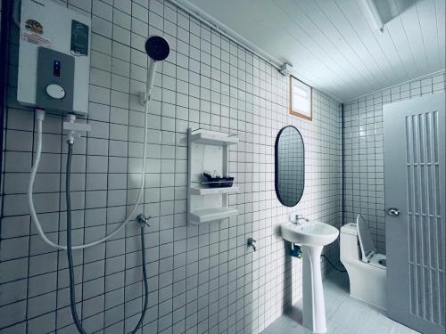 a white tiled bathroom with a shower and a sink at Jin Pool Villa in Ban Khok Chakohan