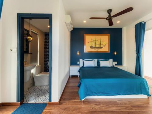 a bedroom with a blue bed and a bathroom at Shadyside 4B in Tân Thành (1)