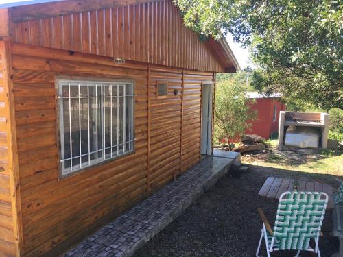 a wooden building with a window and a chair at Cabaña Flor Serrana in Tanti