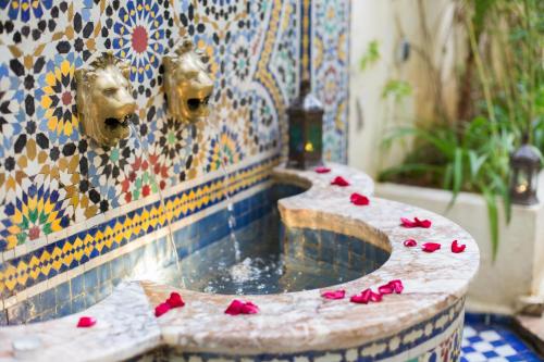 una fuente con pétalos de rosa roja en una pared de mosaico en Riad Jardin Chrifa, en Fez