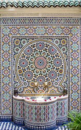 a bathroom with a tile wall with a sink at Riad Jardin Chrifa in Fès