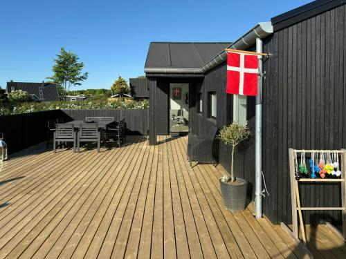 a wooden deck with a flag on a house at Renovated Holiday Home With Sea View In Skåstrup in Bogense