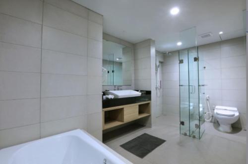 a bathroom with a shower and a toilet and a sink at Quest Prime Cikarang by ASTON in Bekasi