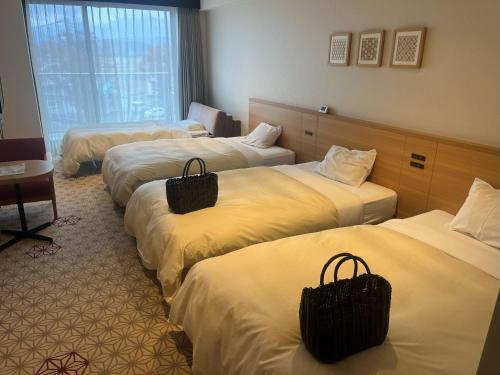 a hotel room with three beds with baskets on them at Hotel Kadoman in Aso