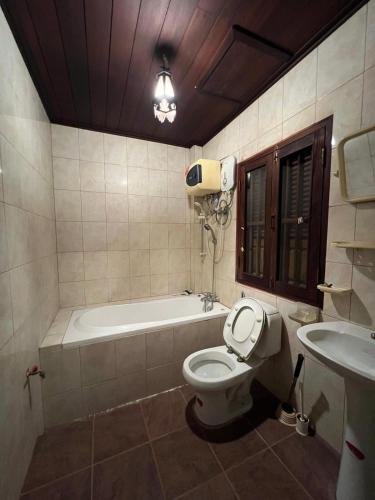 a bathroom with a tub and a toilet and a sink at Mary's House Xiengthong in Luang Prabang