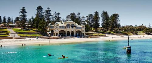 persone su tavole da surf in acqua di fronte a una spiaggia di Beach House Perth a Perth