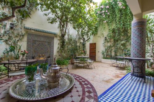 a patio with a tea kettle and tables and trees at Riad Jardin Chrifa in Fès
