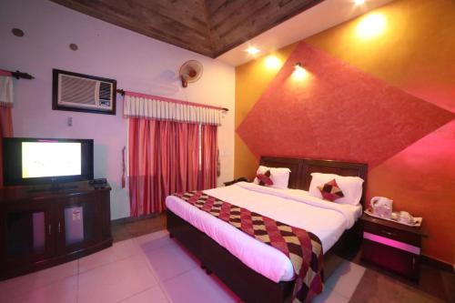 a bedroom with a large bed and a flat screen tv at Kangs Nirvana Resorts and Spa in Hoshiārpur