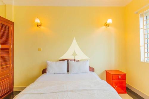 a bedroom with a white bed with two pillows at Serey Sok San Apartment in Phumi Ta Phul