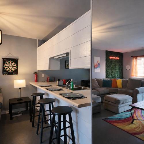 a kitchen and living room with a counter and stools at Heart of Raleigh in Raleigh