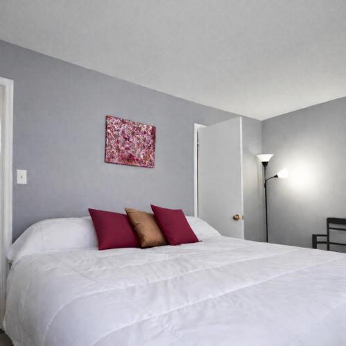 a bedroom with a large white bed with red pillows at Heart of Raleigh in Raleigh