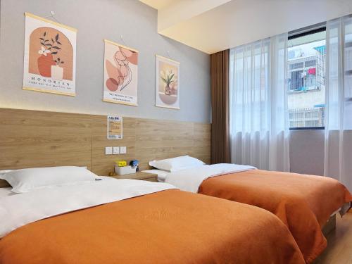 two beds in a hotel room with a window at 恩宜客栈 in Dujiangyan