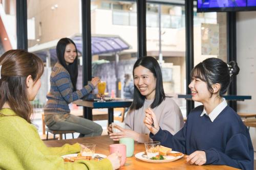 a group of women sitting at a table eating food at Imano Tokyo Hostel in Tokyo