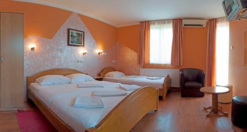 a hotel room with two beds and a chair at Vila Madams - Palić in Palić