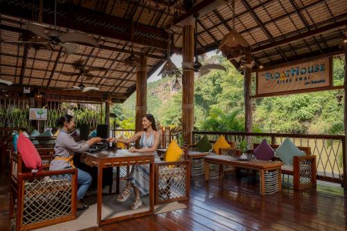 a man and woman sitting at a table in a restaurant at The Float House River Kwai in Sai Yok