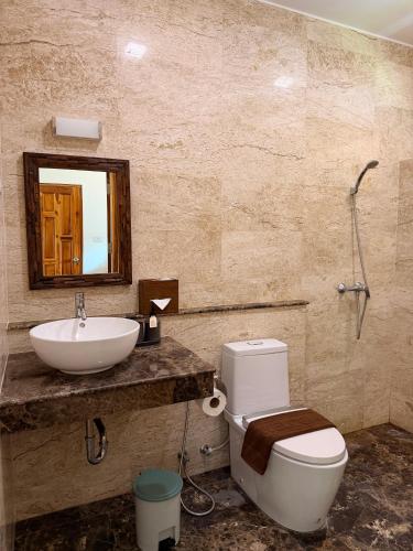 a bathroom with a sink and a toilet and a mirror at Baan Yanikar in Lampang
