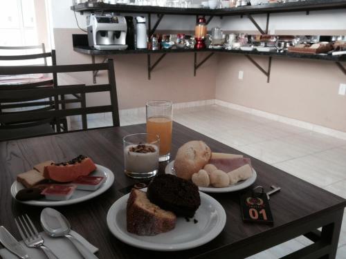 einem Tisch mit zwei Teller Essen und einem Glas Orangensaft in der Unterkunft M & S Hotel in Bauru