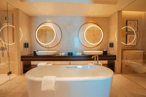 a bathroom with two sinks and a tub and two mirrors at Palm Springs Hotel Dili in Dili