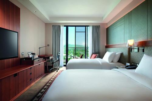 a hotel room with two beds and a flat screen tv at Palm Springs Hotel Dili in Dili