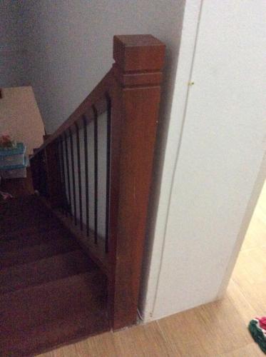 a wooden stairway with a wooden rail in a room at Amaretto Hostel in Surat Thani